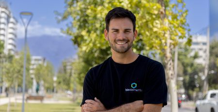 Ignacio Parada sonriendo con los brazos cruzados, vistiendo una camiseta negra con el logo de Bioelements en un entorno natural